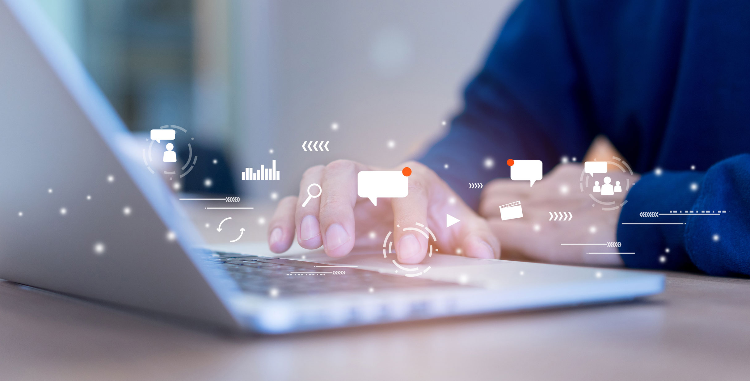 Mains sur un ordinateur portable entourées d’icônes de recherche et de messages